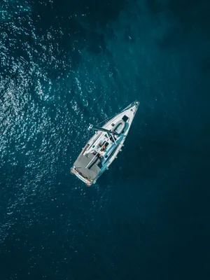 A yacht on deep-blue open water, seen from above.